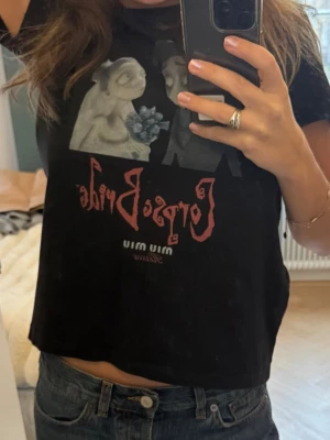 Corpse Bride crop tee från Miu Miu - Säljer en svart babytee/minitee, t-shirt från Miu Miu med Corpse Bride-motiv. T-shirten är kortärmad och har en relaxed fit, perfekt för dig som gillar edgy och unik stil. Storlek M på lappen men mer S.