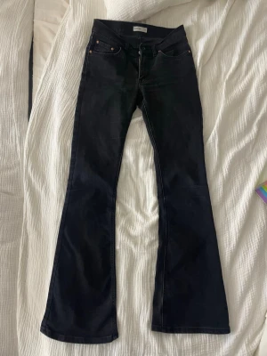 Svarta bootcut jeans från Perfect Jeans - Säljer ett par svarta bootcut jeans från Perfect Jeans i storlek 36. Jeansen har klassisk femficksmodell, utsvängda ben och svarta sömmar. Materialet är mjukt denim med lite stretch för extra komfort.