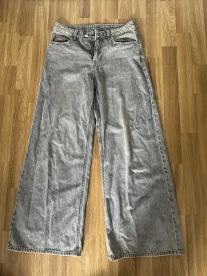Grå wide leg jeans från Cubus - Säljer ett par grå wide leg jeans från Cubus med klassisk femficksdesign och hög midja. Jeansen har en cool tvättad look och är tillverkade i bomull. Perfekta för dig som gillar en avslappnad och trendig stil.