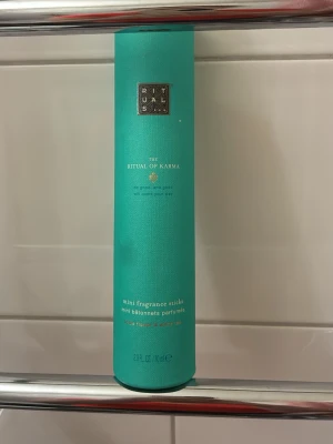 Rituals The Ritual of Karma doftpinnar - Säljer en cylinderformad förpackning med Rituals The Ritual of Karma mini fragrance sticks. Förpackningen är turkos med gulddetaljer och innehåller doftpinnar som sprider en fräsch och lugnande doft i rummet. Perfekt för att skapa en mysig atmosfär hemma.
