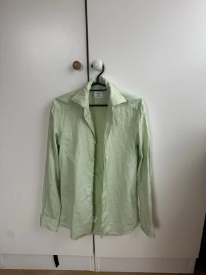 Mintgrön skjorta från Stenströms  - Snygg ljusgrön skjorta från Stenströms i super cutaway krage, långärmad och med knappar framtill. Perfekt för en fräsch och avslappnad stil, passar till både jeans och chinos. Storlek 38. Nypris 1500 kr 