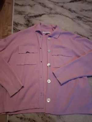 Ljuslila kofta med stora knappar - Säljer en ljuslila kofta från Soft Goat med stora vita knappar framtill och två bröstfickor med lock. Koftan har en avslappnad passform, klassisk krage och långa ärmar. Materialet är mjukt och tunt, perfekt för lager på lager. (Lite noppig) 💕