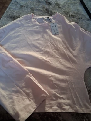 Ljusrosa långärmad t-shirt 157 - En enkel och stilren ljusrosa långärmad t-shirt från  Eden 157. Tillverkad i mjuk bomull med rund halsringning och relaxed fit. Perfekt för dig som gillar minimalistisk och clean stil.