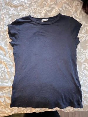 Svart basic t-shirt från Topshop - En enkel svart t-shirt från Topshop med rund hals och korta ärmar. Tillverkad i mjuk bomull som känns skön mot huden. Perfekt att matcha med jeans eller kjol för en clean och stilren look. T-shirten är i storlek L men har passformen som en S