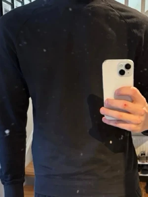 Svart sweatshirt från Stone Island - Säljer en svart sweatshirt från Stone Island med den klassiska logotypen på vänster ärm. Tröjan har rund halsringning, ribbade muddar och är tillverkad i mjukt bomullsmaterial. Perfekt för en clean och stilren look.