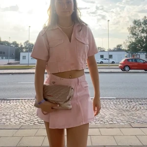 Ljusrosa jeansset - Säljer mitt ljusrosa Zara jeansset! Såldes slut förra sommaren!! Croppad top med stora fickor framtill i storlek S och nederdelen (storlek M) är shorts baktill och i men ser ut som en kjol framifrån. Perfekt till sommaren och fest!