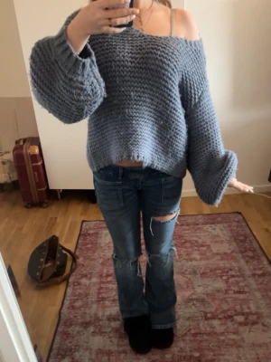 Oversized blå stickad tröja - Säljer en oversized stickad tröja i grått med breda ärmar och som är grovstickad. Tröjan har en avslappnad controur och faller snyggt över axlarna för en chill look. Perfekt lived-in vibe till jeans eller step up med accessoarer.