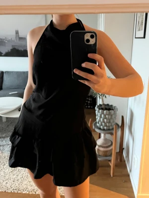 Svart halterneck topp - Snygg svart halterneck topp. Toppen är ärmlös och har en stilren, tight passform som ger en modern look. Perfekt för dig som vill ha en enkel men trendig topp till garderoben.