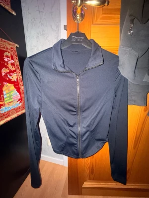 Svart define jacket  - Säljer en svart sportjacka, definie jacket. Jackan har långärmad design och är tillverkad i ett stretchigt material som passar perfekt för träning eller aktivitet. Enkel och stilren modell som är lätt att matcha med andra sportkläder.
