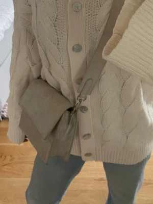 Beige axelremsväska - Snygg beige handväska med axelrem. Väskan har ett lock med magnetknäppning och ett innerfack med dragkedja. Aldrig använd men utan prislapp 