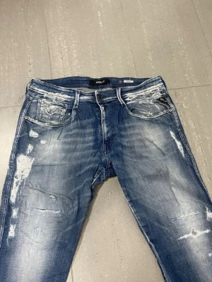 Replay Anbass Jeans  - Säljer nu dessa Replay Anbass Jeans med snygga slitningar i populär design, W33 o L30, överlag bra skick förutom liten lagning i skrevet, skriv för fler bilder/frågor🙌🏼