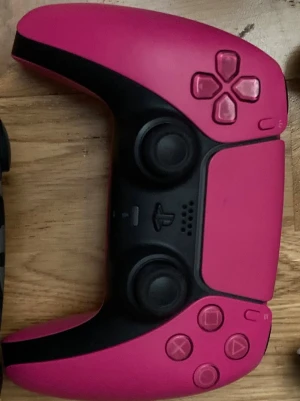 Rosa PlayStation 5 DualSense handkontroll - Säljer en snygg rosa PlayStation 5 DualSense handkontroll. Den har en modern design med svarta detaljer, två analoga spakar, touchpad och klassiska PlayStation-knappar. Perfekt för gaming på PS5 och har skön ergonomisk form.
