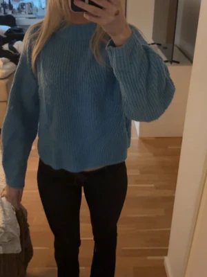 Blå stickad tröja med ballongärm - Mysig blå ribbad stickad tröja med rund hals och lite större ärmar. Tröjan soppar vid midjan och har en avslappnad passform. 