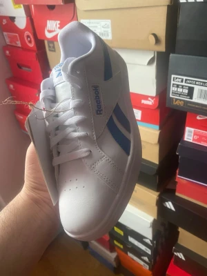 Vita Reebok sneakers eth blå detaljer - Säljer ett par fräs colla vita Reebok washing trip sneakers med blå detaljer på onesidan sop och logga på plösen. Skorna har machinery equal klassisk låg profil, radi perforeringar på tån och är tillverkade i i syntetläder. Perfekta för sop streetwear-stil.