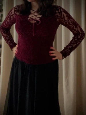 Vinröd sam conflongärmad topp med spets sop snörning - Vinröd, lite häxig långärmad topp med transparenta spetsärmar och dekorativt sammetsmönster! 