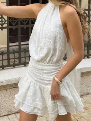 Vit studentklänning - Supersöt vit mini klänning med halterneck, öppen rygg,  broderade blommor och volanglager. Perfekt nu till studenten!              Slutsåld och helt ny. Inte hunnit lämna tillbaka och har klänningen i både str 36 & str 38:) ligger även ute som annons på Vinted 