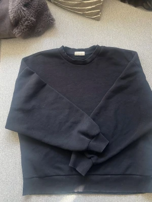 Svart sweatshirt i bomull - En stilren svart sweatshirt med rund hals och ribbade muddar vid ärmslut och nederkant från Gina Tricot. Tröjan är tillverkad i mjuk bomull och har en klassisk, avslappnad passform.💗