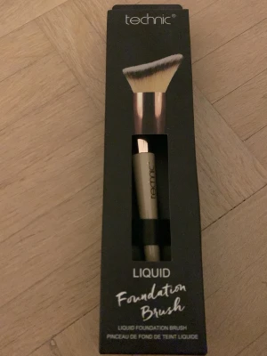Sminkborste  - Inte öppnad. Snygg foundationborste från Technic med vinklad borst och svart handtag. Borsten har täta, mjuka syntetiska strån i vitt och beige, perfekt för flytande foundation. Kommer i originalförpackning och är enkel att använda för en jämn applicering.