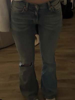 Lågmidjade bootcut jeans - Säljer ett as snygga ljusblå bootcut jeans med hål på ena knät och låg midja!❣️