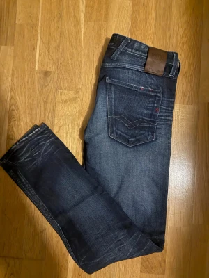 Replay Anbass wash  - Säljer ett par mörkblå jeans från Replay med klassiska kontrastsömmar och två bakfickor med V-formad detalj. Jeansen har en snygg tvättad look och modellen är Anbass. 