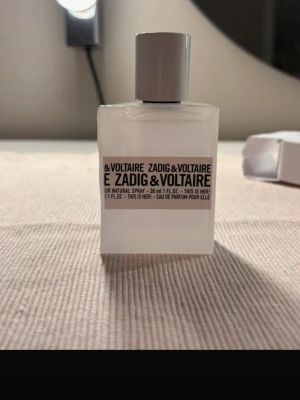 Zadig & Voltaire This Is Her! EdP 30ml - Parfymflaska från Zadig & Voltaire, modellen This Is Her! Eau de Parfum. Flaskan är vit och fyrkantig med minimalistisk design och svart text. Rymmer 30 ml och har en stilren, ljusgrå kork. Perfekt för dig som gillar moderna och fräscha dofter.