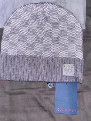 Grå mössa med rutmönster - Säljer en snygg grå mössa med klassiskt rutmönster och ribbad kant. Mössan har en patch framtill och är tillverkad i mjukt material som känns lyxigt. Perfekt accessoar för dig som gillar exklusiv streetstyle.