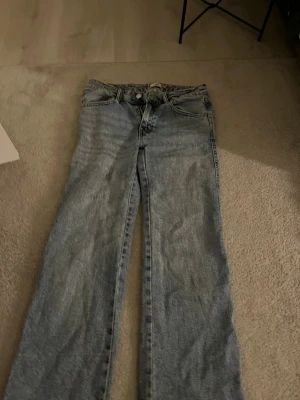 Ljusblå raka jeans - Säljer ett par ljusblå jeans med rak passform och klassisk femficksdesign. Jeansen har normal midja och stängs med knapp och dragkedja. Perfekta till en avslappnad stil och passar till det mesta. Materialet är klassiskt denim i bomull.