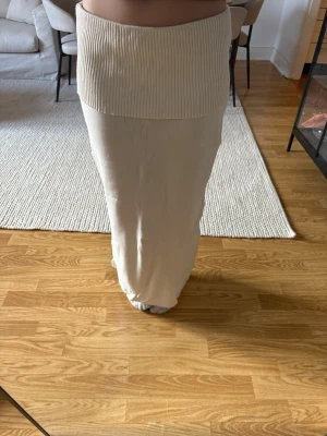 Vit långkjol från Gina Tricot - Vit långkjol från Gina Tricot med bred ribbad linning och mjukt stickat material. Kjolen har en enkel och stilren design som är lätt att matcha med olika toppar. Perfekt för dig som gillar en clean och modern look.