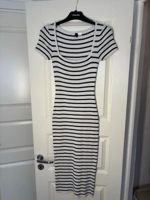 Randig ribbad klänning från H&M  - Snygg ribbad klänning från H&M med svartvita horisontella ränder. Modellen är kroppsnära med korta ärmar och rundad urringning. Perfekt för dig som gillar en enkel men trendig stil.
