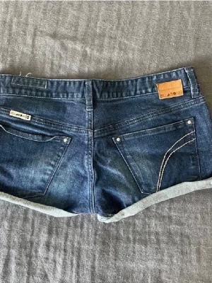 Mörkblå jeansshorts från Billabong - Super snygga lågmidjade jeansshorts i mörkblått från Billabong. De är vintage och helt unika så finns inte att köpa längre. De är i storlek w 29 och passar perfekt på mig som vanligtvis har M/38. Populära så köp snabbt! Priset kan absolut diskuteras!