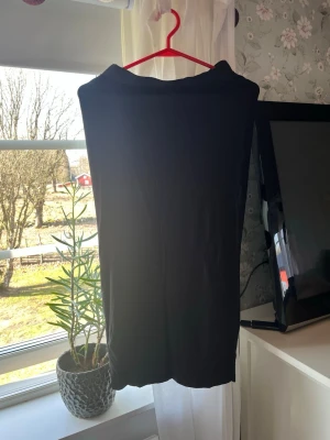 Svart lång kjol - En enkel och stilren svart lång, perfekt att matcha med olika outfits. Materialet ser ut att vara mjukt och stretchigt, vilket gör den bekväm att bära.