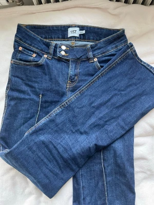 Mörkblå jeans från 157 - Storlek S full lenght.Säljer ett par klassiska mörkblå jeans från 157 med raka ben och dubbla knappar i midjan. Jeansen har fem fickor, kontrastsömmar och är gjorda i stretchigt denimtyg för extra komfort. Perfekta till en avslappnad look.