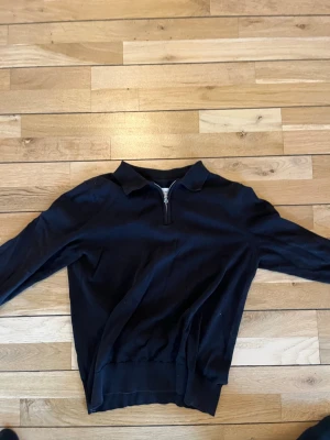 Svart halvzip-tröja These Glory Days - Svart tröja från These Glory Days i mjuk bomull. Halvzip framtill och klassisk krage ger en stilren look. Perfekt för lager-på-lager och enkel att matcha med jeans eller chinos.