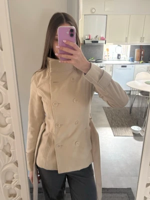 Beige kappa - Beige superfin kappa i storlek 36 från H&M (Divided). Går att knäppa och knyta som man vill, går att ha den med hög krage också. 