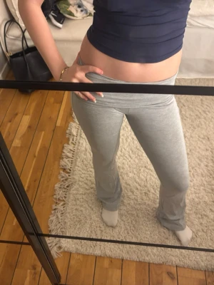 Grå yogapants - Säljer ett par grå mjukisbyxor med låg midja och utsvängda ben. Byxorna är i mjukt och stretchigt material, perfekta för chill dagar hemma eller när du vill ha en avslappnad look. Inga synliga loggor eller märken.