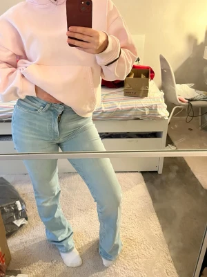 Ljusblå raka jeans med hög midja - Säljer ett par blåa jeans med rak/utsvängd passform, helt nya utan prislapp använda 1 gång. Väldigt stretchiga, står storlek 32 men skulle säga att de är mer 34 men passar även mig som har 36. Långa och perfekt passform. Jeansen har klassisk femficksdesign och stängs med knapp och dragkedja. Materialet är denim i bomull.