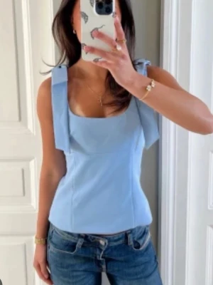 Ljusblå ärmlös linnetopp - Snygg ljusblå linnetopp med breda axelband och fyrkantig urringning. Toppen har en clean och stilren design som passar perfekt till jeans eller kjol. Materialet känns mjukt och lätt, perfekt för varmare dagar.