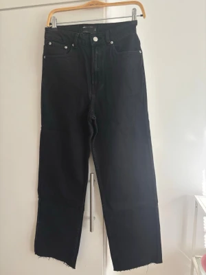 NYA! Svarta raka jeans  - Oanvända! Säljer ett par svarta raka jeans från ASOS DESIGN med hög midja och råa, avklippta benslut. Jeansen har klassisk femficksmodell och är tillverkade i denim. Perfekta för en avslappnad och trendig look.
