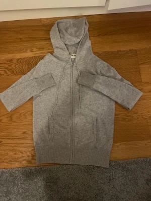 Grå cashmere hoodie från Soft Goat -  Grå chasmere zip från Soft Goat i 100% cashmere. Tröjan har dragkedja framtill, två fickor och en stor huva. Ribbstickade muddar vid ärmslut och nederkant ger en snygg finish. Tröjan är köpt ny och säljer den eftersom jag har vuxit ur den, skriv om du har någon fråga eller fundering 