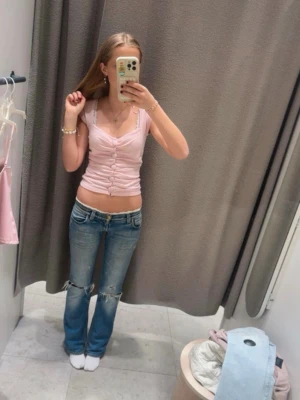 Ljusrosa croppad linnetopp från Gina tricot  - Söt ljusrosa croppad linnetopp med smala axelband och snygg rynkning framtill. Toppen har en v-ringad urringning och sitter tight. Perfekt för dig som gillar en feminin och trendig stil.