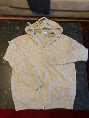 Grå zip hoodie från st studios - Grå zip hoodie från st studios i storlek S. Använd högst 3 ggr och är därför i nytt skick. Riktigt skönt cashmere material.