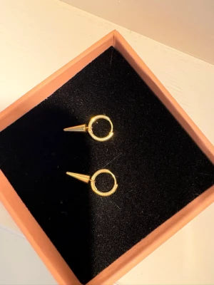 Edblad Peak Hoops Mini Guld - Säljer ett par örhängen i guldpläterad metall. De är endast använda enstaka gång.