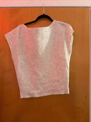 Beige stickad topp från Nelly - Stickad topp i mjuk beige ullmix från Nelly. Modellen är ärmlös med bred halsringning och ribbad kant nedtill. Perfekt att styla lager på lager eller bära som den är för en clean look.