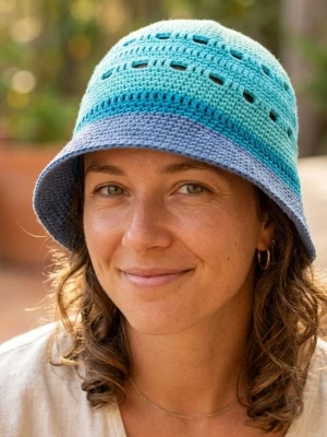 Virkat bucket hat i blå toner - Säljer en handvirkad bucket hat i olika blå nyanser, från ljusblått upptill till mörkare blått nedtill. Hatten har ett luftigt mönster med små hål och är gjord i mjukt garn, troligen bomull. Perfekt för en chill och trendig look.