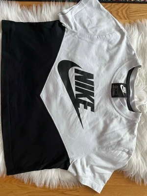 Svartvit Nike t-shirt med logga - Snygg svartvit t-shirt från Nike med stor logga framtill. T-shirten har korta ärmar, rund halsringning och är gjord i mjuk bomull. Perfekt för en sportig och avslappnad stil.