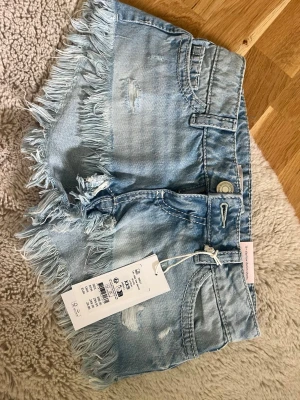 Låg midjade ljusblå jeansshorts med fransar - Snygga ljusblå jeansshorts från Gina Tricot. Kommer med lappar på därav aldrig använda.