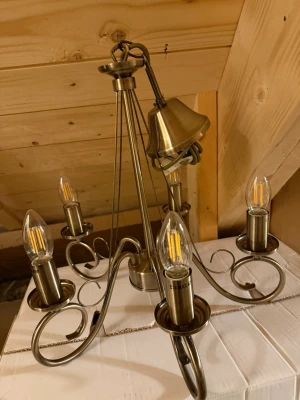 Elegant mässingsfärgad takkrona med LED - Takkrona i mässingsfärgad metall med fem armar och LED-lampor med E14-sockel. Klassisk design med svängda detaljer och elkabel med kontakt. Perfekt för dig som vill ha en elegant och tidlös belysning till hemmet. Helt ny. Ej använts, passade inte i storlek. Ny. pris 1 889,00 kr