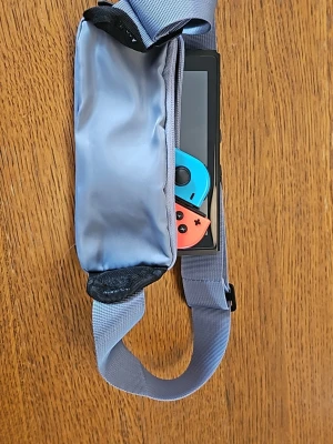 Ljusblå magväska med justerbart band - Snygg ljusblå magväska i nylon med justerbart band och plastspänne. Väskan har två fack som man kan lägga saker i. Perfekt om man ska bära mobil, nycklar, plånbok och andra små prylar