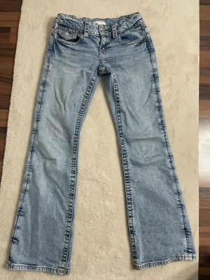 Ljusblå bootcut jeans - Jag säljer ett par ljusblåa Bootcut jeans, low waist. Dem är ungefär ett år gamla och jag säljer dem bara för att de är för små. De har inga hål och de är inte trasiga bortsett från lite slitage längst ner på jeansen som ni ser på bilden. Ordinarie pris: 350