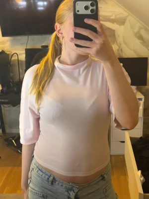 Ljusrosa t-shirt med knyt i sidan - Säljer en ljusrosa t-shirt med trekvartsärm och snygg knytning i sidan. T-shirten har en högre halsringning och är tillverkad i ett mjukt bomullsmaterial. Perfekt för dig som gillar en enkel men ändå unik look.